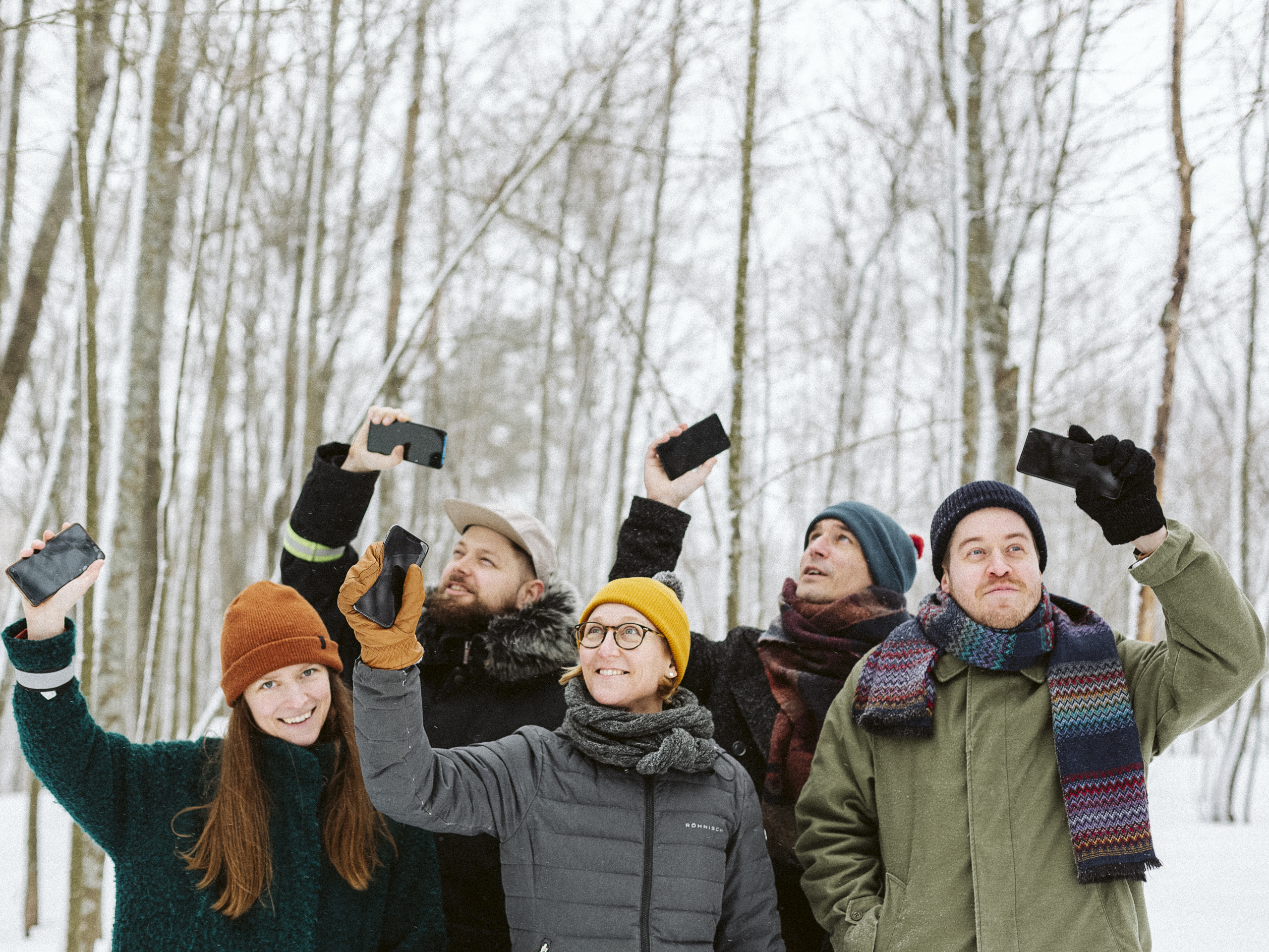 Researchers are in a snowy forest with phones in their hands.