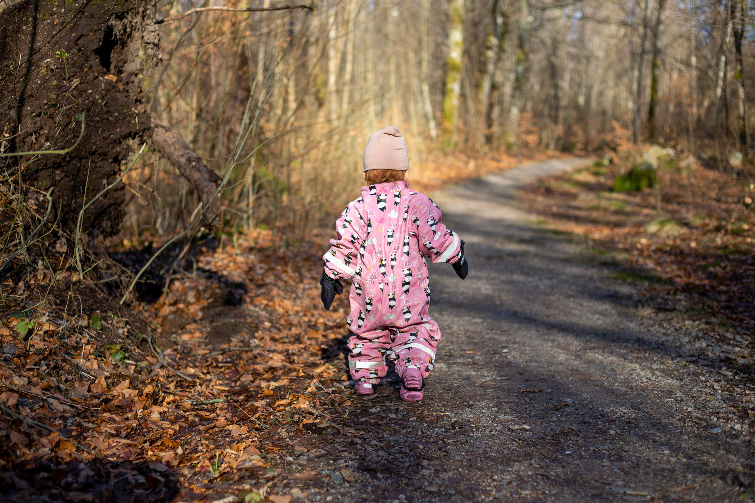 Girl in pink overall running in forest