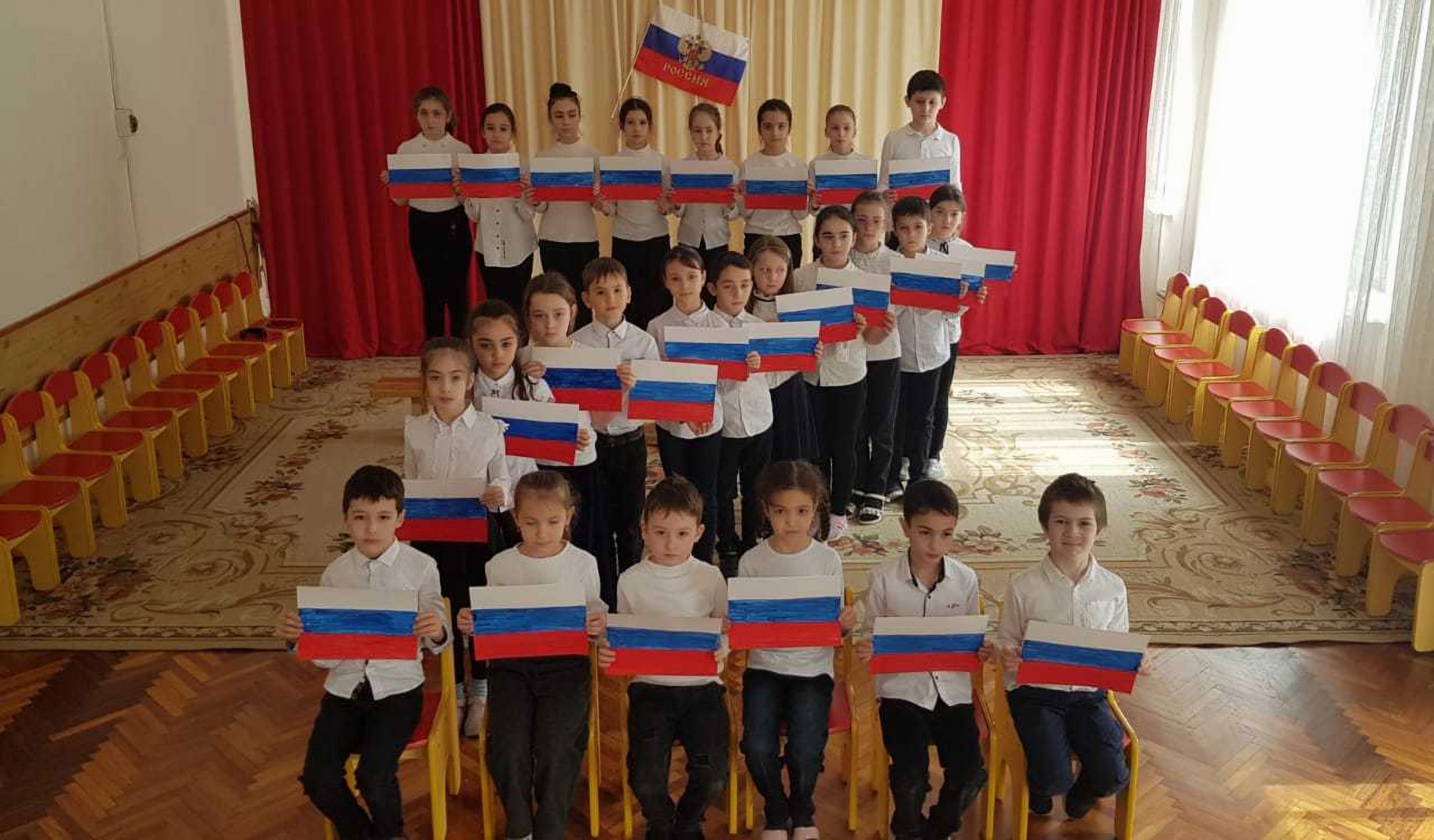 A group of children holding Russian flags standing in a way that forms the letter Z.