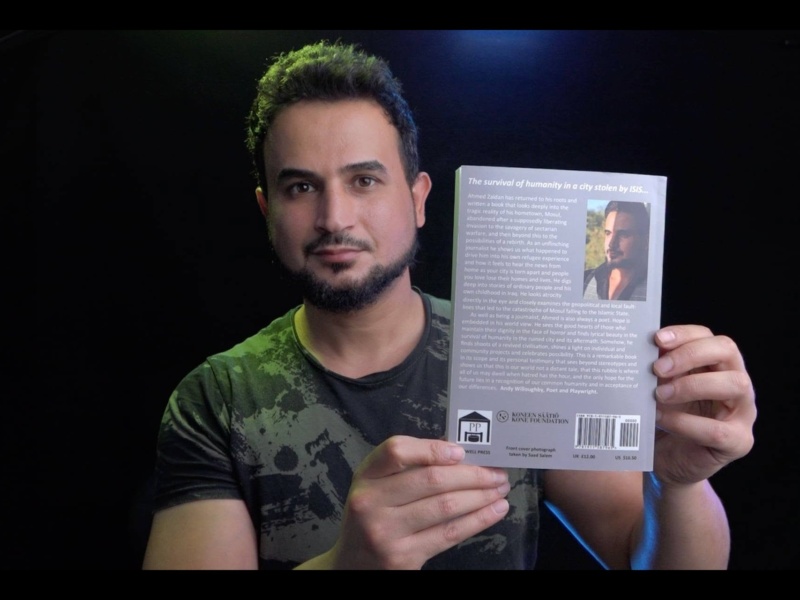 A man holding a book with the back cover facing the camera